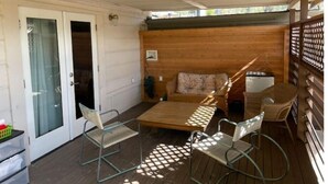 A covered patio with a wooden table, metal chairs, a cushioned bench, and a refrigerator. - Unique studio with cozy patio (La Mesa)