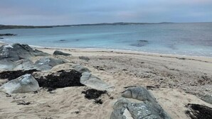 Une plage avec de gros rochers et une eau calme.