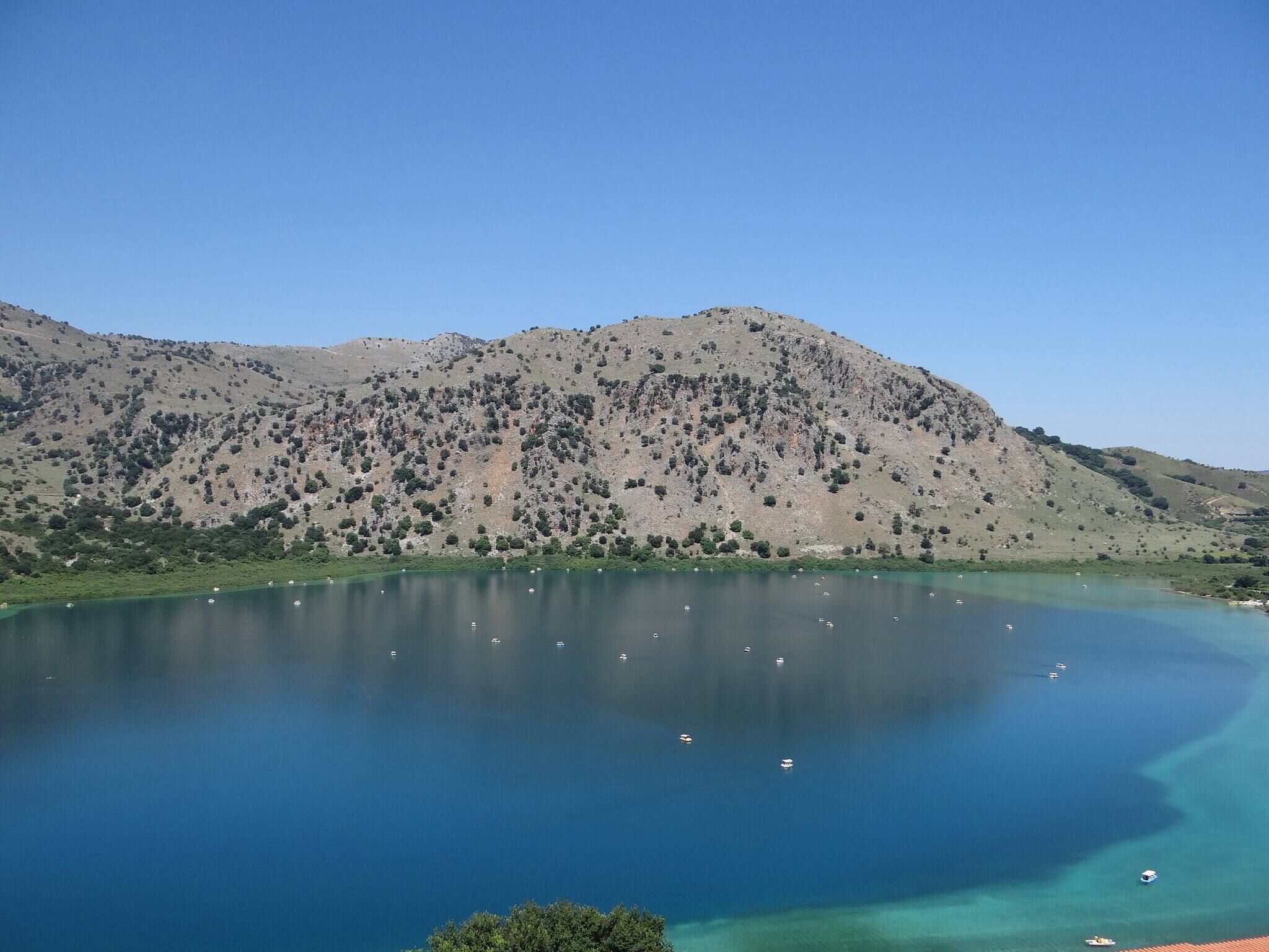 Ein See mit Booten, umgeben von Hügeln.
