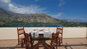 Un tavolo da pranzo con sedie e vista su un lago e montagne.