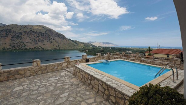 Una piscina in pietra con vista su un lago e montagne.