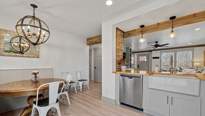 Une cuisine moderne avec une table à manger en bois, des chaises blanches et un lustre.