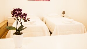 Una stanza con due letti, un'orchidea in vaso e un quadro appeso al muro.