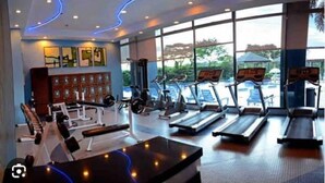 A gym with treadmills, weight machines, and a bench. - CityScape Condo: Vibrant & Central BGC (Taguig)