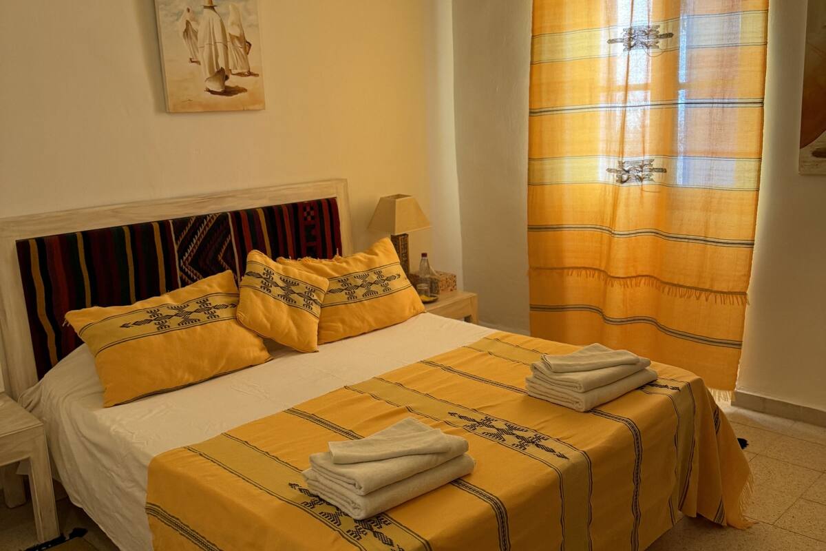 Una habitación de hotel con una cama grande, una mesita de noche, una lámpara y un cuadro en la pared.