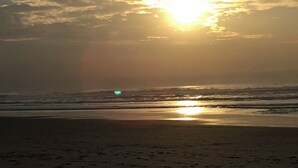 A beach with the sun setting over the horizon, creating a silhouette of the landscape. - Dar Lola (Houmt Souk)