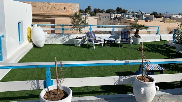 A rooftop terrace with artificial grass, outdoor seating, and potted plants. - Dar Lola (Houmt Souk)