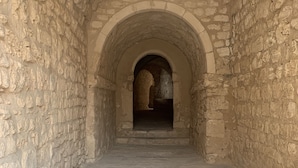 A stone corridor with an arched entrance leading to a darker interior. - Dar Lola (Houmt Souk)