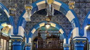 An interior with blue and white arches, wooden benches, and hanging light fixtures. - Dar Lola (Houmt Souk)