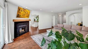 A modern living room with a fireplace, a large painting, a sofa, and a coffee table. - Serene Lake Retreat (Westlake Village)