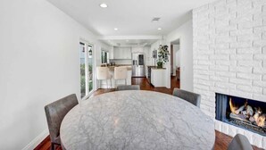 A modern living room with a marble table, comfortable seating, a fireplace, and a view of the kitchen in the background. - Serene Lake Retreat (Westlake Village)