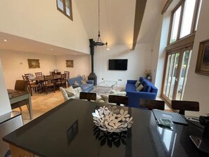Relax in this stylish living area with a high ceiling, large windows, and a cozy fireplace.