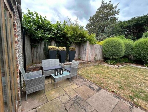 Relax in a serene outdoor space with a wicker sofa, chairs, and a small table.