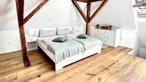 A bedroom with a wooden ceiling structure, a white bed, and a wooden floor. - Old villa in the heart of Lorsch (Lorsch)