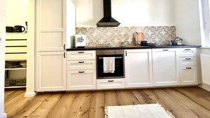 A kitchen with white cabinets, a black range hood, and patterned backsplash. - Old villa in the heart of Lorsch (Lorsch)