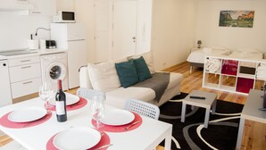 Un apartamento moderno y bien iluminado con comedor, kitchenette y sala de estar con sofá y televisor.