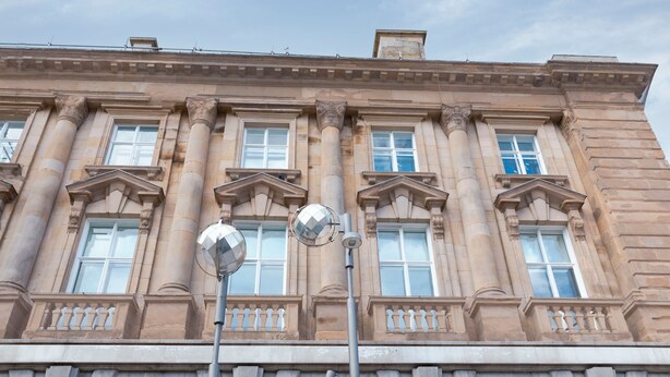 Un edificio clásico con amplias columnas, ventanas simétricas y un balcón con barandilla.