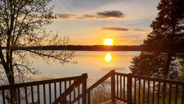 Una terraza de madera con vista a un lago tranquilo al atardecer.