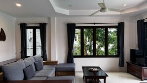 Un soggiorno moderno con un divano componibile, un tavolino da caffè, una televisione e un ventilatore a soffitto.