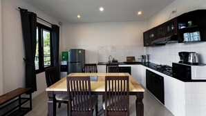Una cucina compatta con un tavolo da pranzo, sedie, un frigorifero, un lavandino e un fornello.