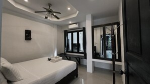 Una camera da letto moderna con un letto, una ventola a soffitto, un condizionatore d'aria, uno specchio e una porta che dà su un balcone.
