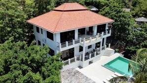 Un edificio a più piani con tetto in tegole rosse, immerso nel verde.