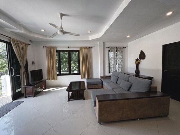 A modern living room with a sofa, TV, and ceiling fan.