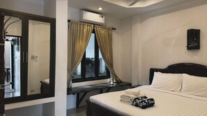 Ein Hotelzimmer mit Bett, Schreibtisch, Spiegel, Deckenventilator und Klimaanlage.