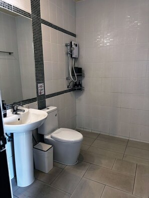 A bathroom with a white sink, toilet, and shower. There is a black and white tiled backsplash, and a small trash bin is visible.