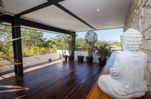 A modern interior with a wooden floor, a stone wall, and a Buddha statue.