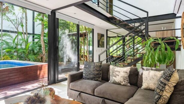 Una sala de estar moderna con un sofá gris, una mesa de centro y una escalera.