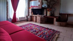 Une pièce chaleureuse avec une cheminée, un canapé rouge et un tapis à motifs.