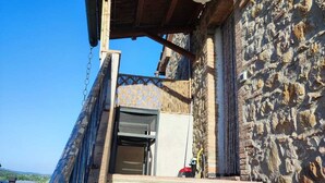 Un bâtiment en pierre avec un escalier en bois menant à une entrée abritée.
