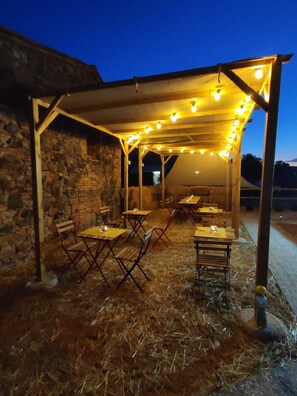 An outdoor patio area with tables and chairs under a wooden pergola, surrounded by stone walls. - Apartment in the heart of the Tuscan Maremma... (Ribolla)