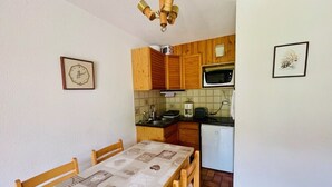 Une cuisine compacte avec des meubles en bois, un four à micro-ondes, un évier et une table à manger avec des chaises.