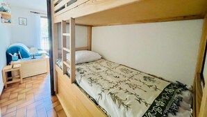 Une chambre avec un lit superposé, un plancher en bois, un petit bureau et une chaise.