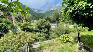 Un sentier en bois mène à un point de vue sur la montagne, avec un bâtiment rustique en arrière-plan.