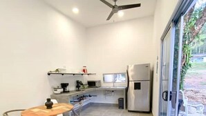 Une cuisine moderne avec un coin repas, un ventilateur de plafond et une vue dégagée grâce à de grandes portes-fenêtres coulissantes.