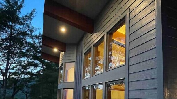 A deck with a sofa and a bed visible through large windows, suggesting a guest room. - Wild Thing - Blowing Rock, Hot Tub, Big Views, NEW (Lenoir)