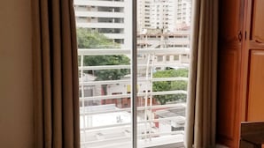 Ein Zimmer mit einer großen Schiebeglasdoor zu einem Balkon, einem Holzschrank und einem Fliesenboden.