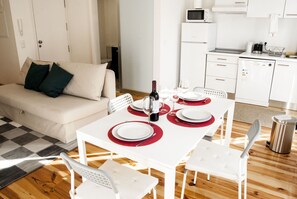 Un salon moderne et bien éclairé, avec un coin repas aménagé pour quatre personnes.