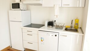 Una cucina compatta con frigorifero, forno a microonde, tostapane e lavello.