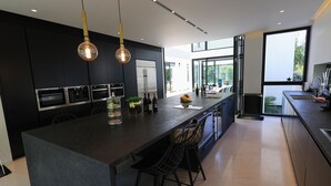 Een moderne keuken met een groot eiland, roestvrijstalen apparatuur en een groot raam voor natuurlijk licht.