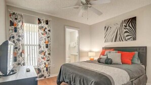 A bedroom with a bed, a desk, a television, and a ceiling fan. - Lake View Villa. Peaceful, 3 bed family home away from home. (Clermont)