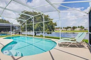 Una piscina con area coperta, circondata da una recinzione, e vista su un lago e case sullo sfondo.