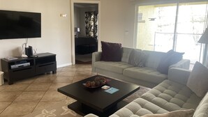 A living room with a sofa, coffee table, TV, and entertainment unit. - Lake View Villa. Peaceful, 3 bed family home away from home. (Clermont)