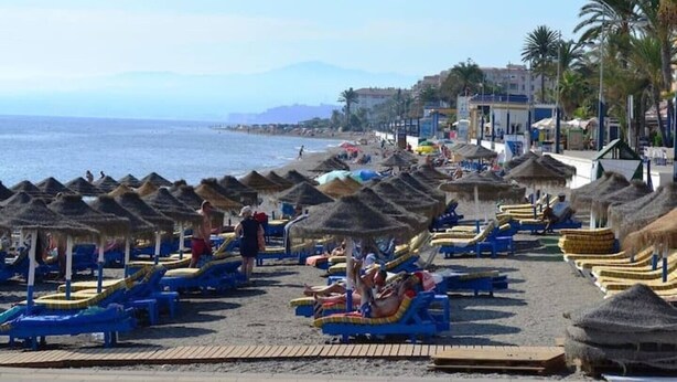 A beach with thatched-roof huts and sun loungers. - Sea View Apt Steps to Beach (Málaga)