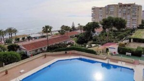 A swimming pool with a view of the ocean and a high-rise building in the background. - Sea View Apt Steps to Beach (Málaga)