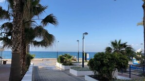 A paved walkway with palm trees and street lamps, leading to a beach. - Sea View Apt Steps to Beach (Málaga)