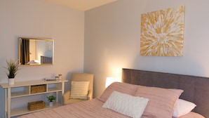 A bedroom with a bed, a chair, a nightstand, a mirror, and a wall art piece. - Cozy-Hoosier themed bungalow-Walk to best city parks and Downtown. (Bloomington)